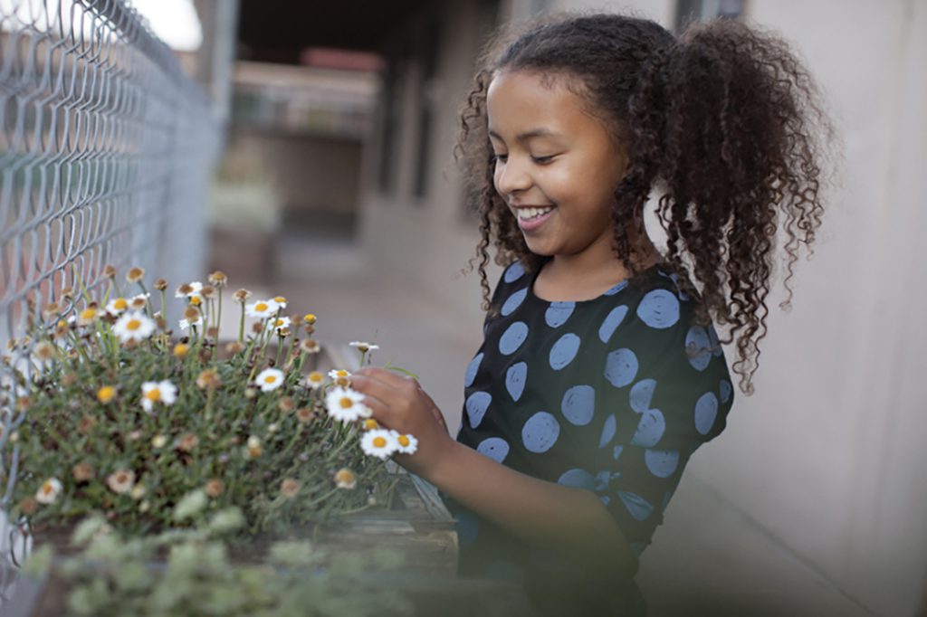 A girl smiling and looking at a flower patch