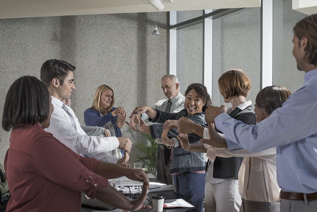 Group of adults doing wrist stretches in a conference room