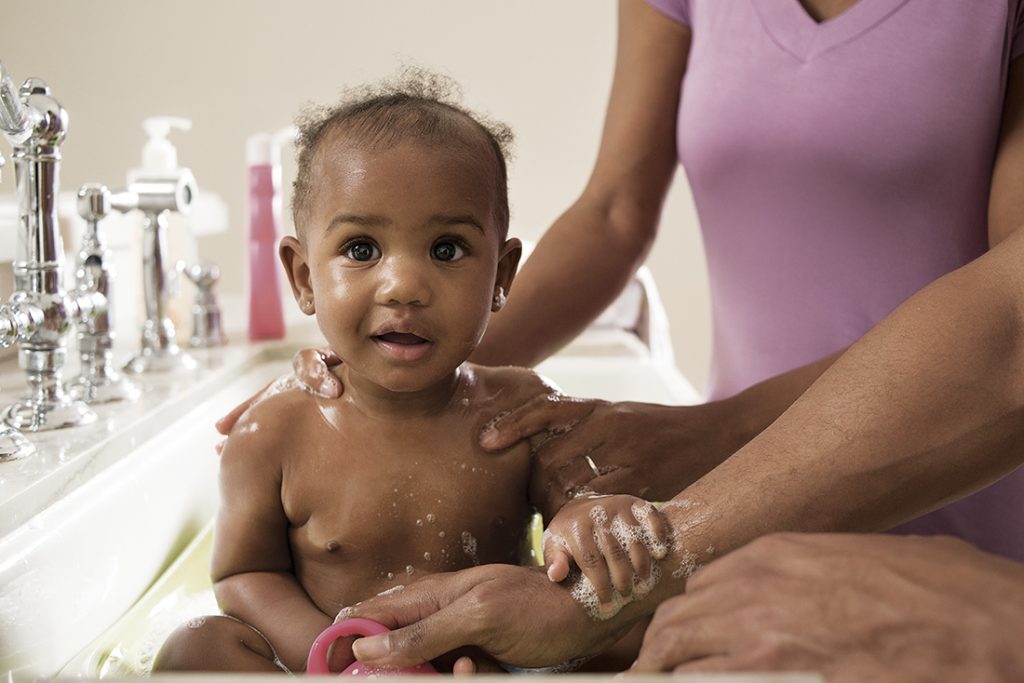 A baby getting a bath in a sink