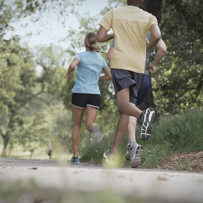Three people going for a run on a path through some trees