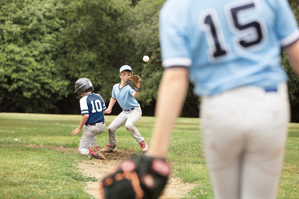 Young man catching a ball at a little league baseball game.