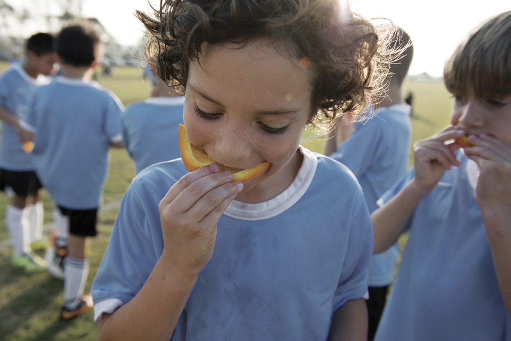 Soccer Boy eating Orange