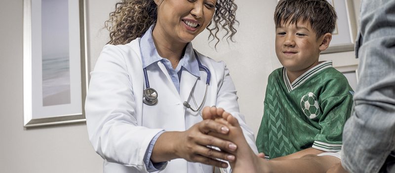 Female doctor examining a young boy's foot